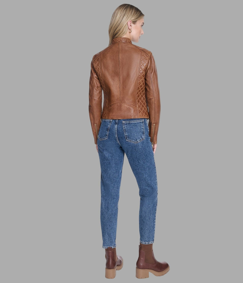 Woman wearing a brown leather jacket and blue jeans on a gray background