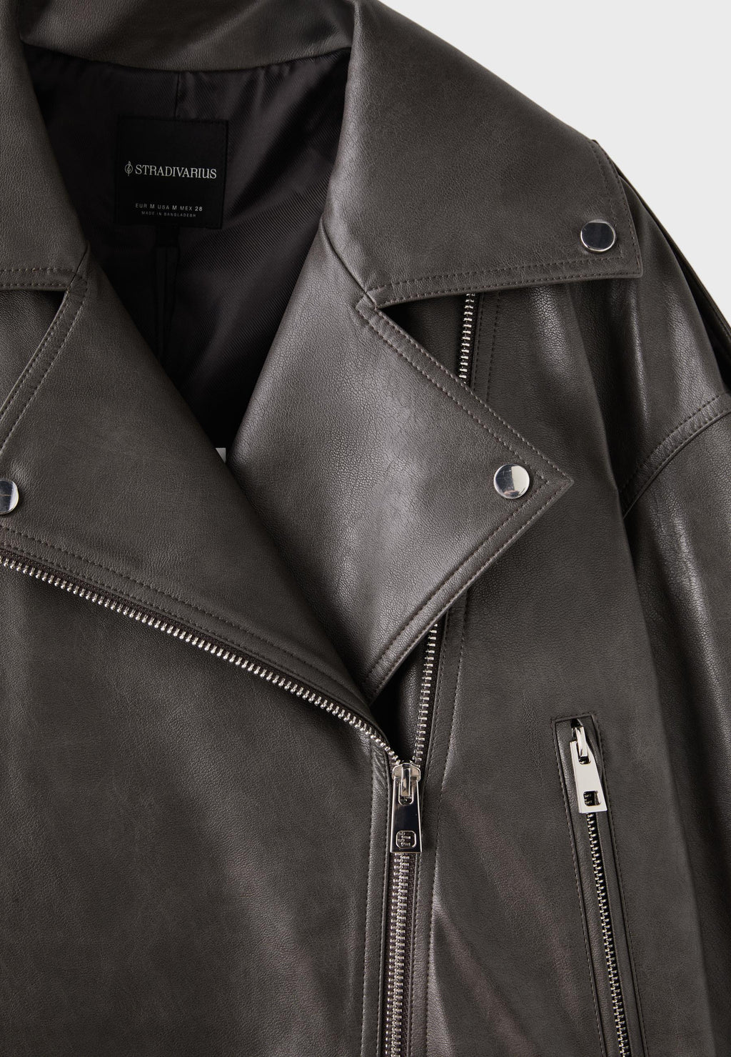 Close-up of a dark gray leather biker jacket with an asymmetrical zipper and a silver snap button.