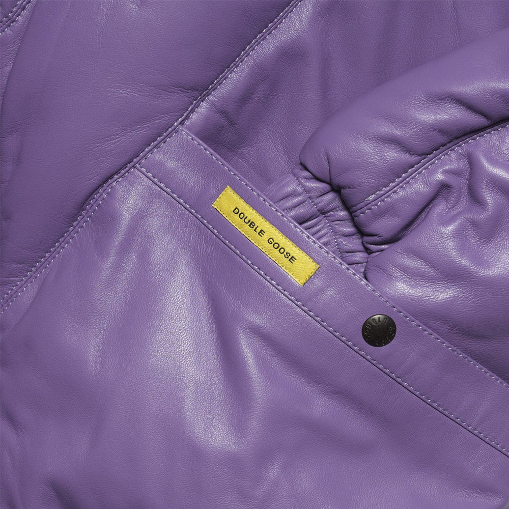 Close-up of a purple leather jacket showing a yellow fabric label that reads 'DOUBLE GOOSE' and a black snap button.