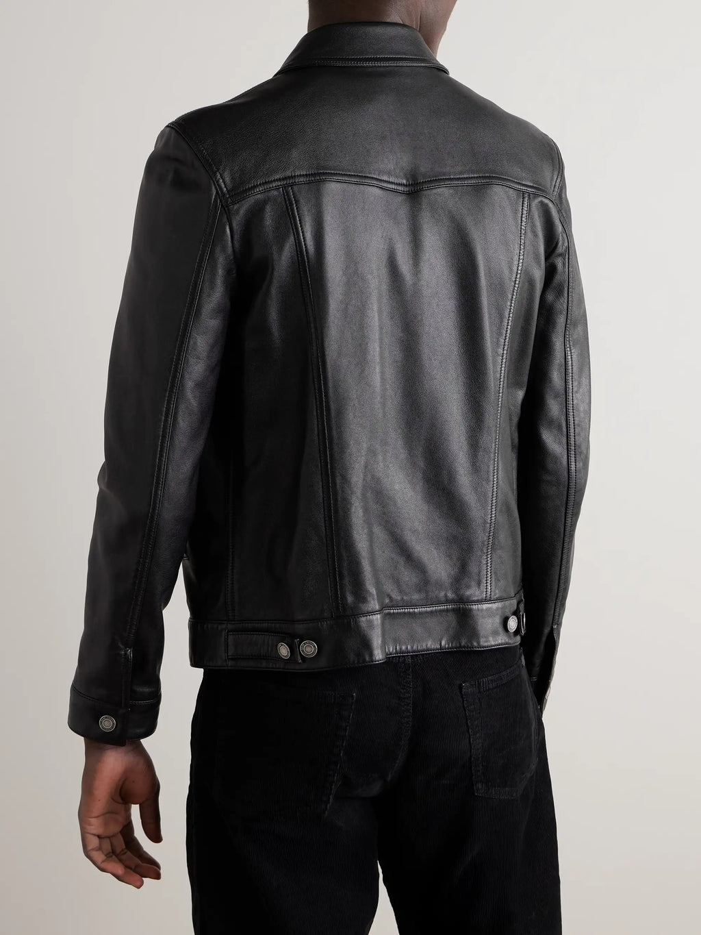 A man wearing a black leather jacket, shown from the back against a light gray studio background.