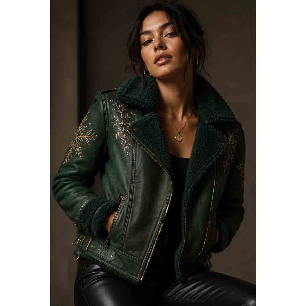 A woman wearing a dark green leather jacket with a fuzzy dark green shearling collar and gold embroidered snowflake patterns on the shoulders, posed against a dark brown background.