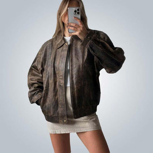 Person wearing a brown leather jacket and white dress against a plain background