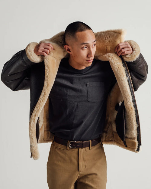 Man wearing a brown shearling jacket with a plain background