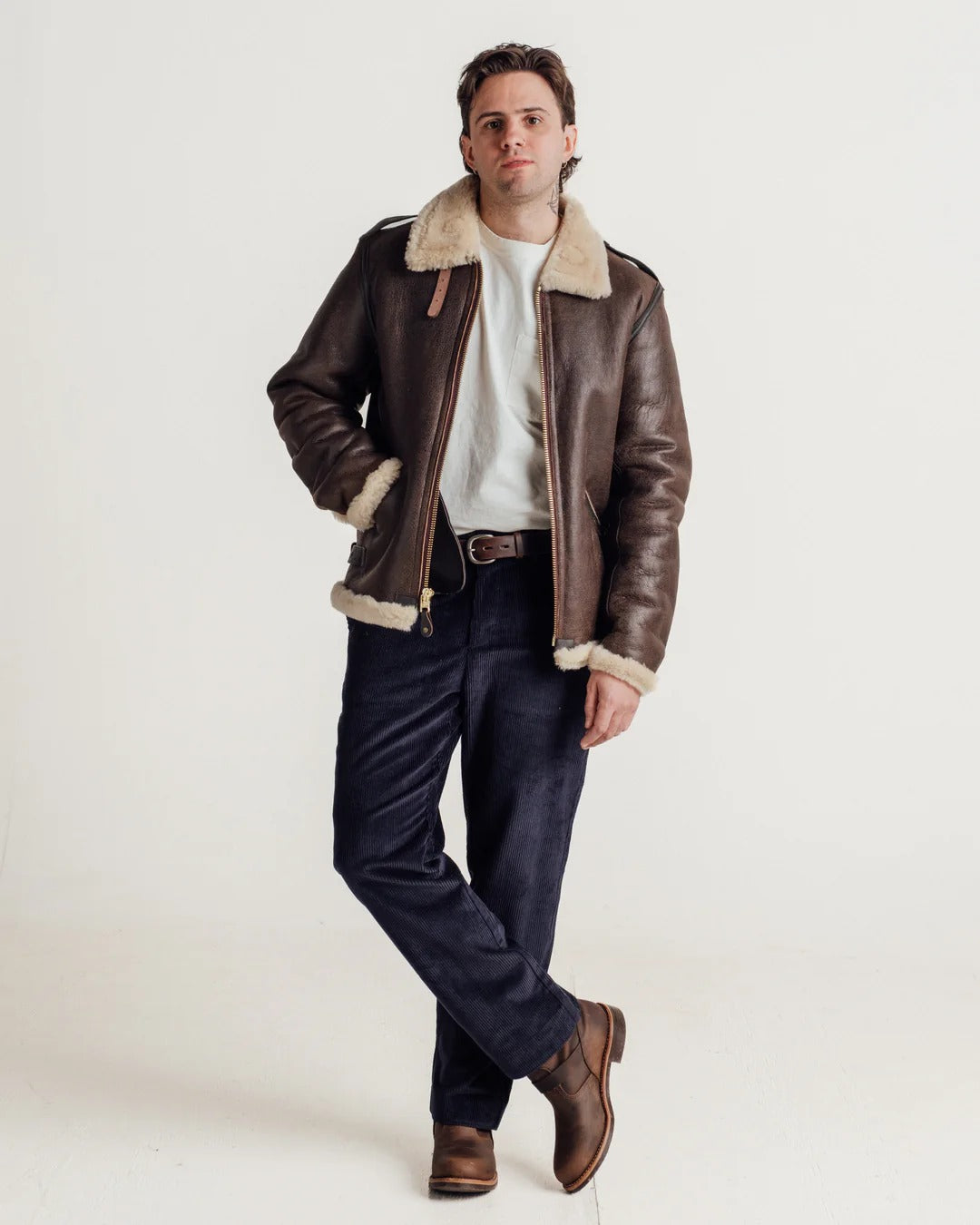 Man wearing a brown leather jacket with shearling collar on a white background
