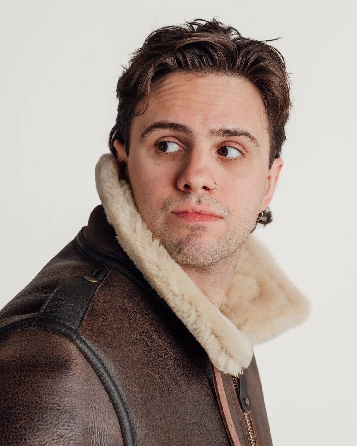 Man wearing a brown leather jacket with a fur-lined hood on a white background