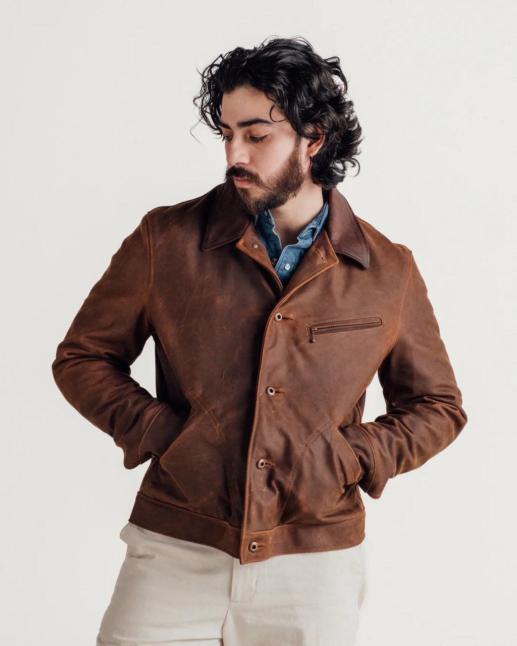 Man wearing a brown leather jacket on a plain background