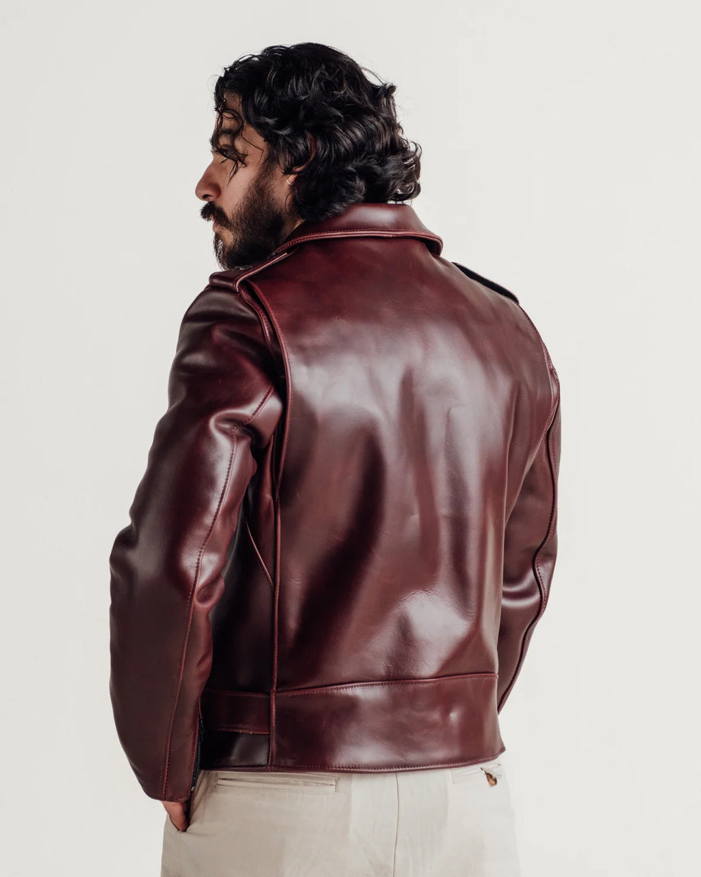 Man wearing a leather jacket and showing back view on a plain background