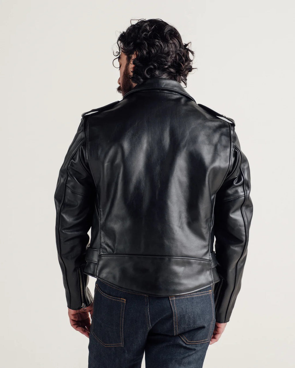 Person wearing a black leather jacket on a plain background