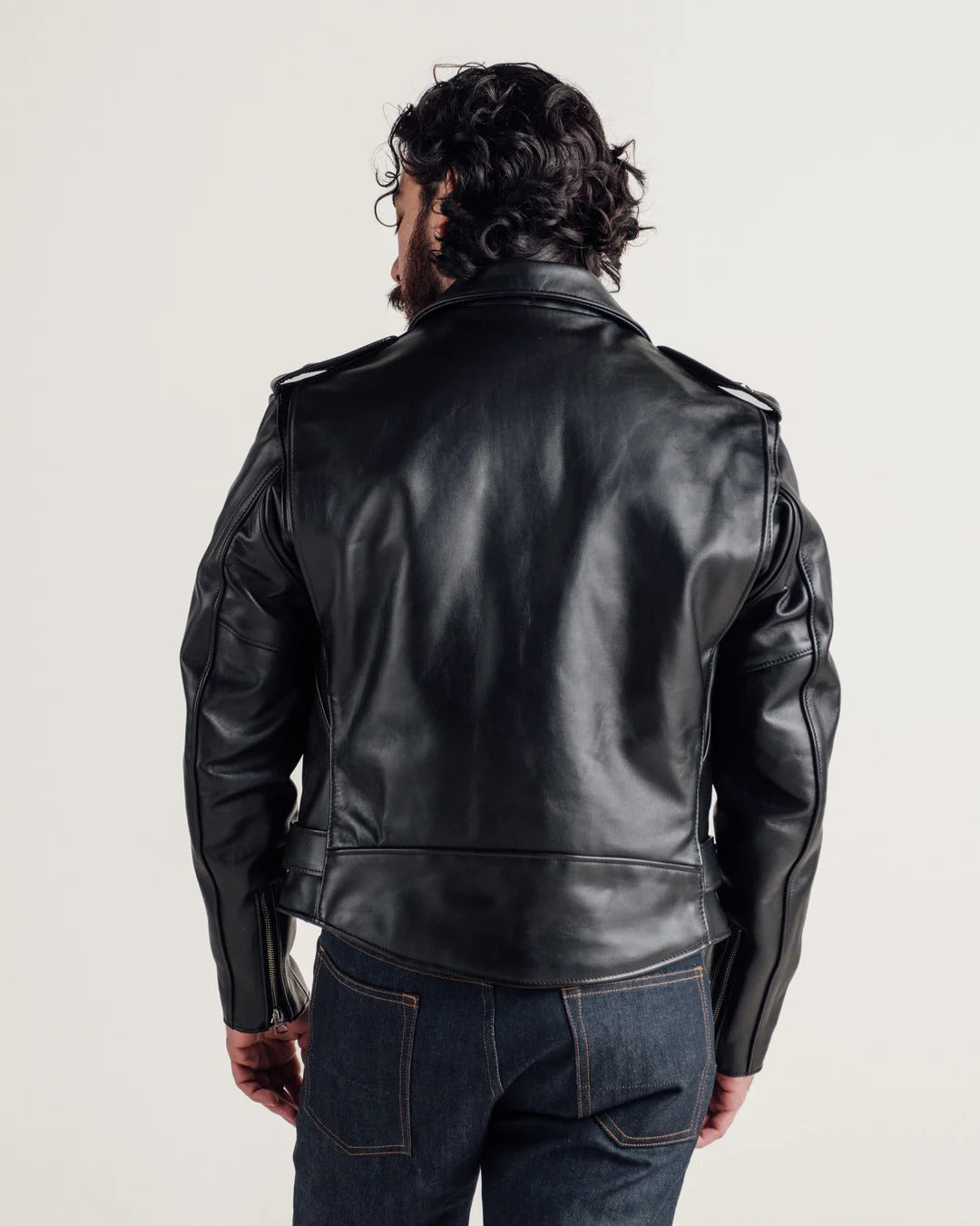 Person wearing a black leather jacket on a plain background