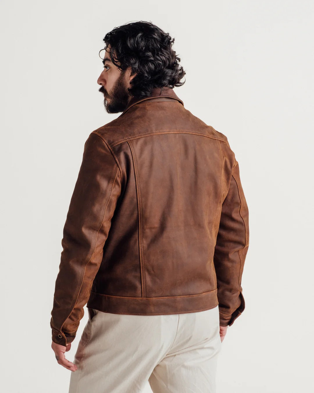 Man wearing a brown leather jacket on a plain background