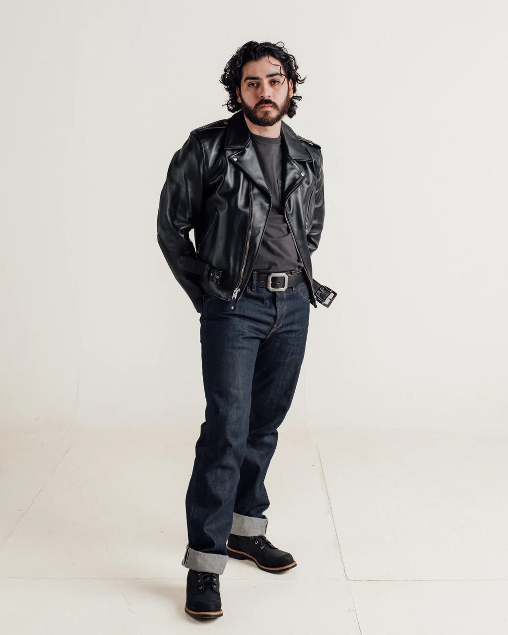 Man wearing a black leather jacket and dark jeans on a white background
