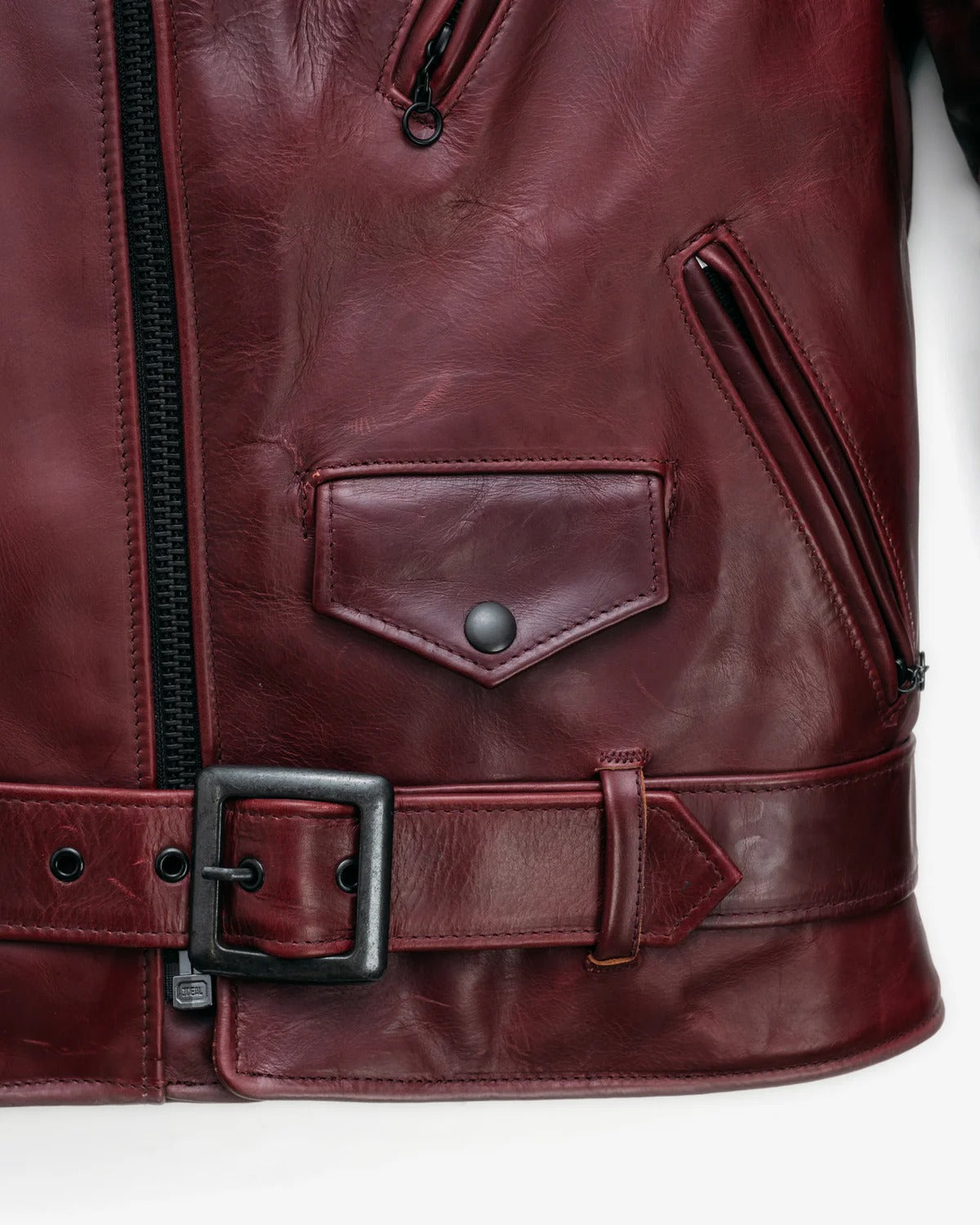 Close-up of a burgundy leather jacket with a belt and zipper on a white background