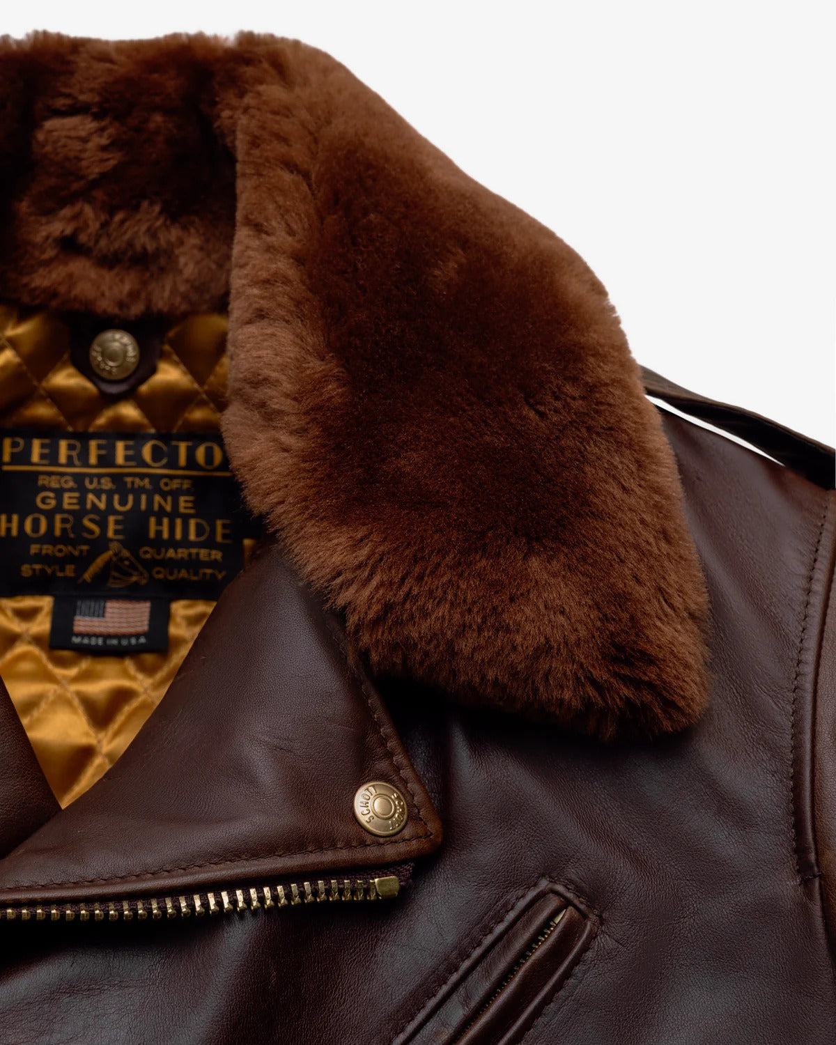 Close-up of a brown leather jacket with fur collar and 'Perfecto' label.