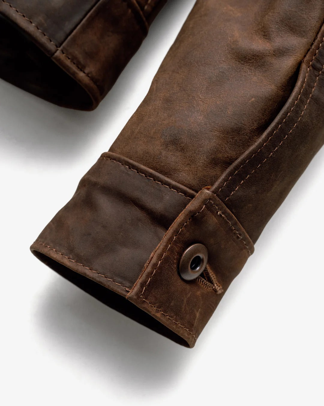 Close-up of a brown leather sleeve with a button on a white background