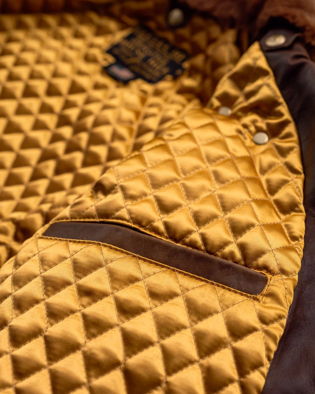 Close-up of a quilted mustard yellow jacket with brown accents