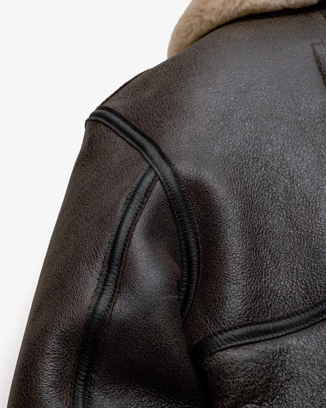 Close-up of a brown leather jacket with fur lining on a white background