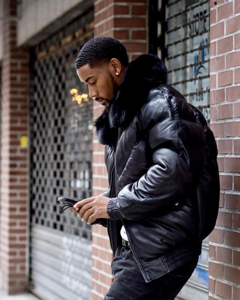 Men wearing black goose country bomber jacket while using phone