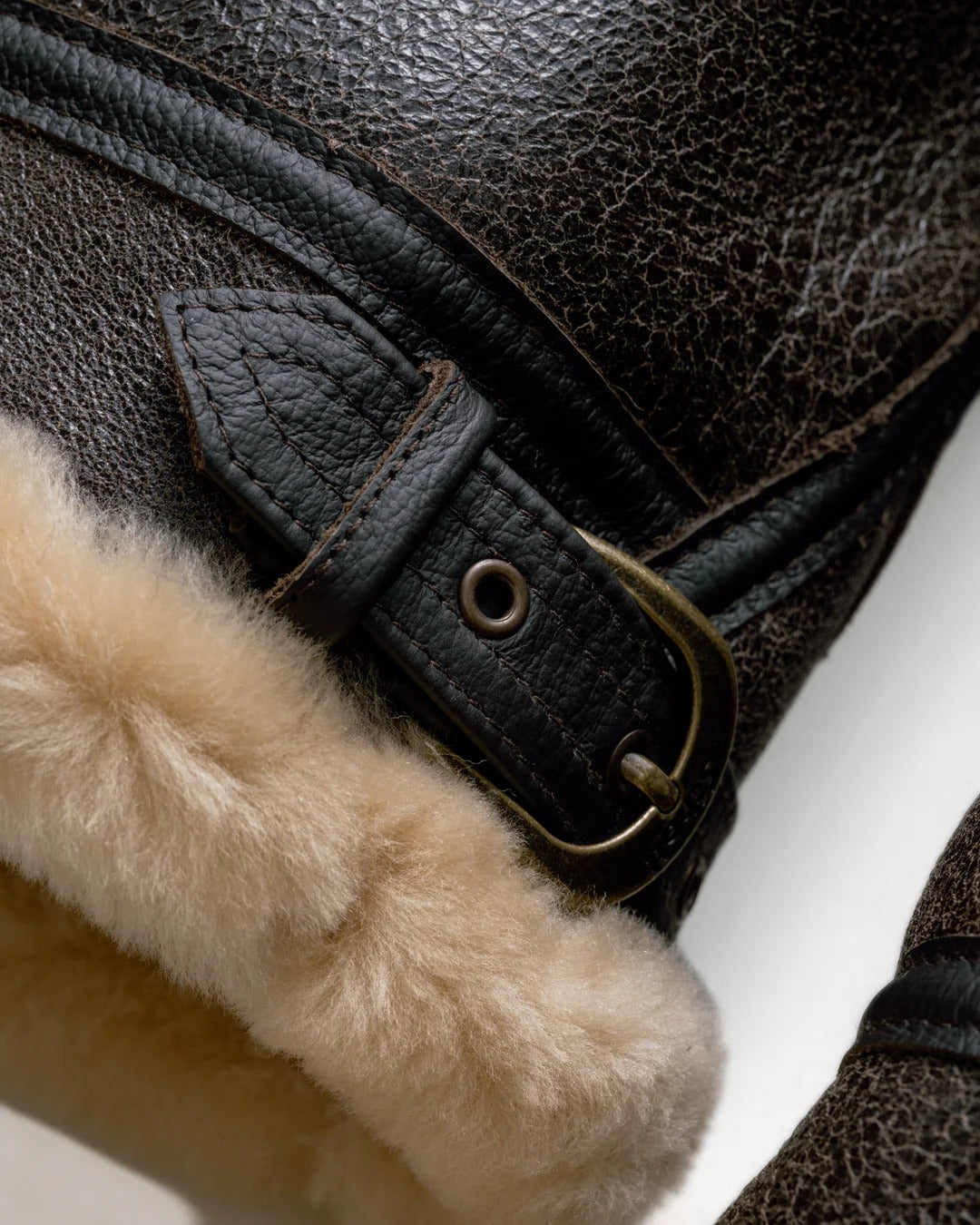 Close-up of a black leather boot with fur lining and a buckle.