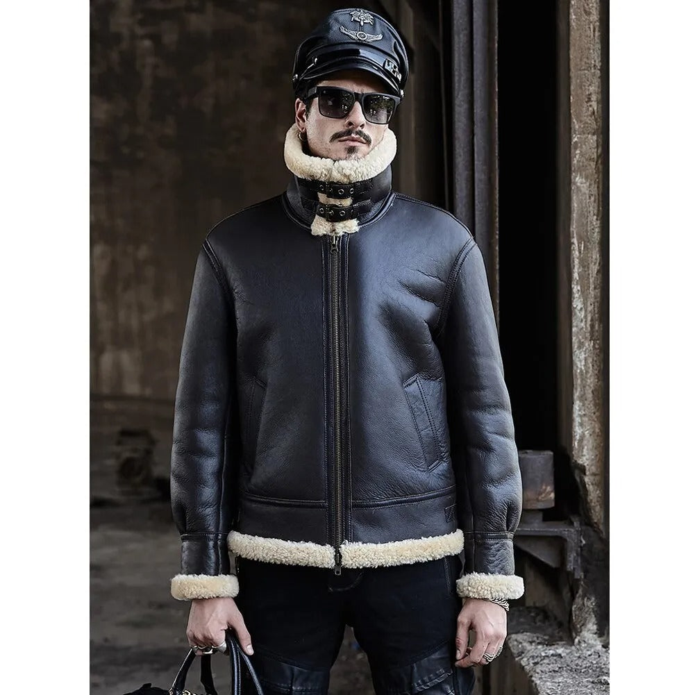 Man wearing a dark leather jacket with white fur trim, sunglasses, and a cap in a rustic setting.