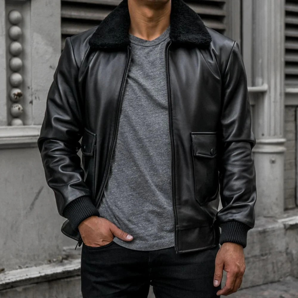Person wearing a black leather jacket with a gray shirt underneath, standing against a building.