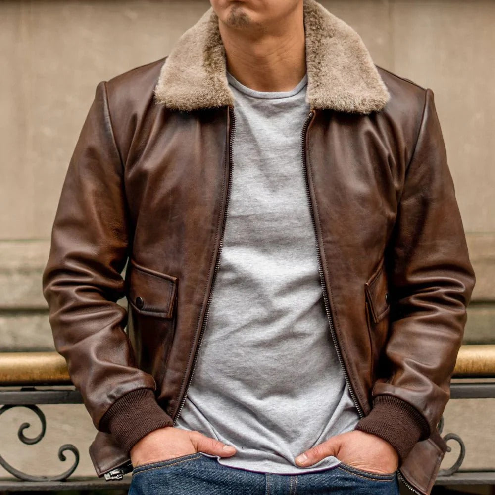 Person wearing a brown leather jacket with a fur-lined collar, standing against a neutral background.