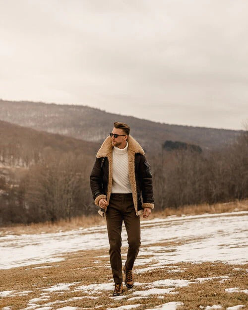 Man wearing brown shearling leather semi-long aviator coat styled with dark jeans and boots in winter