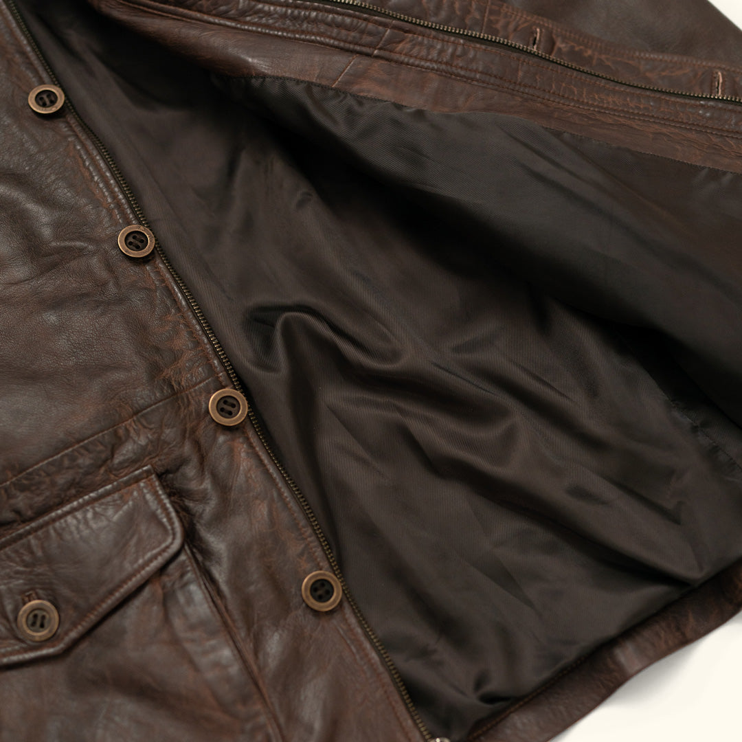 Close-up of a brown leather jacket with buttons and a zipper.
