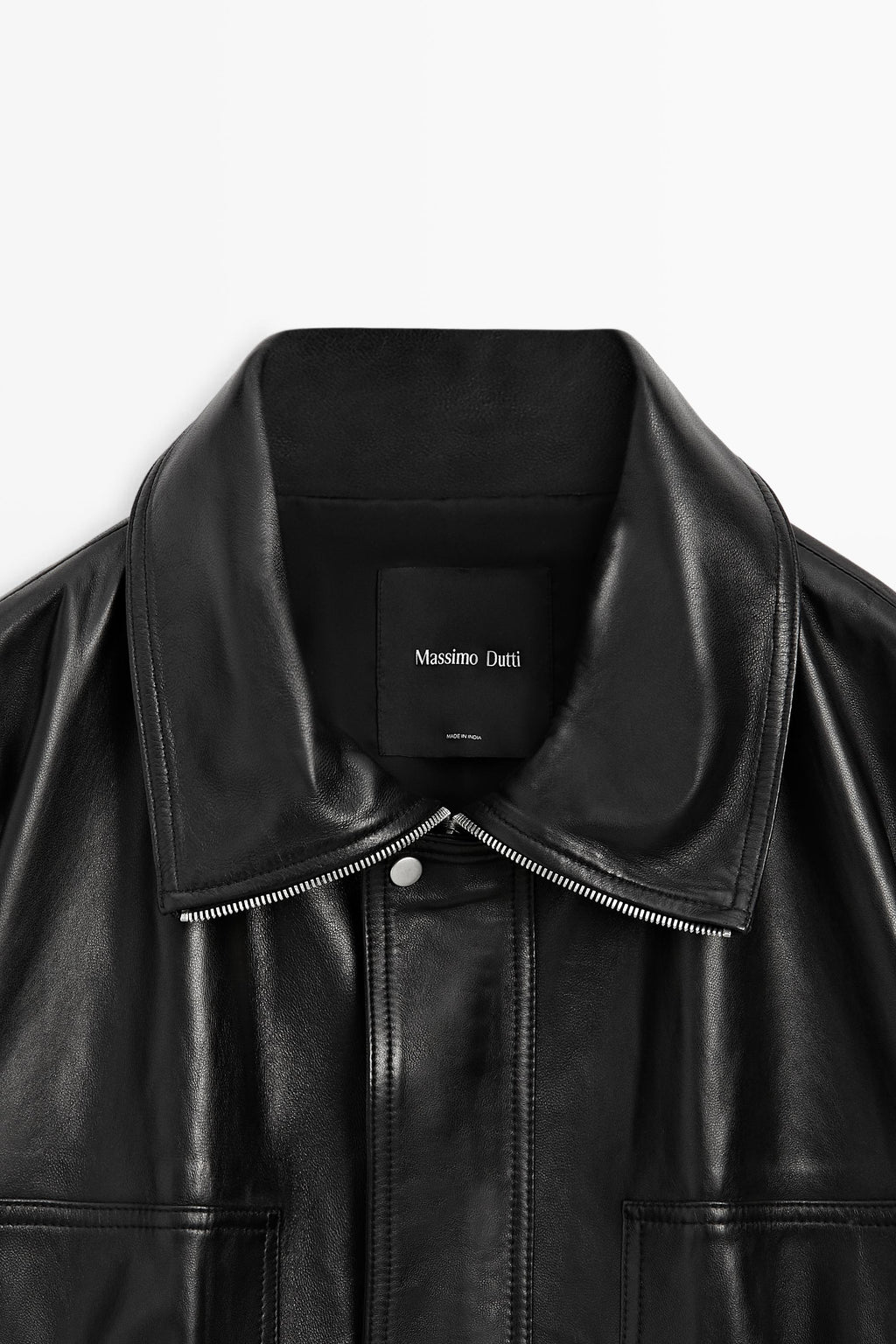 Close-up of a black leather jacket with a wide collar, silver-tone zipper, and a black neck label reading Massimo Dutti.