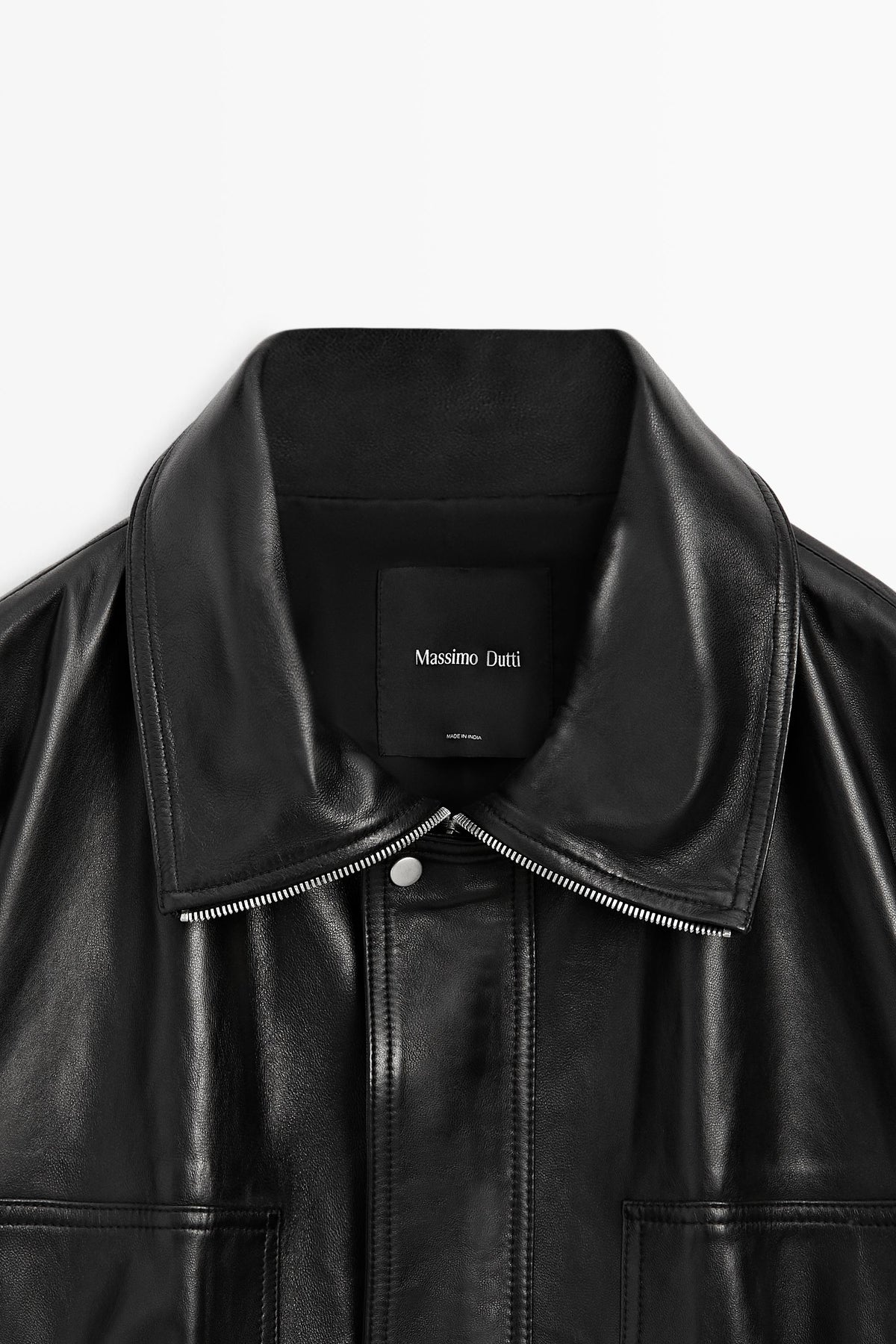 Close-up of a black leather jacket with a wide collar, silver-tone zipper, and a black neck label reading Massimo Dutti.