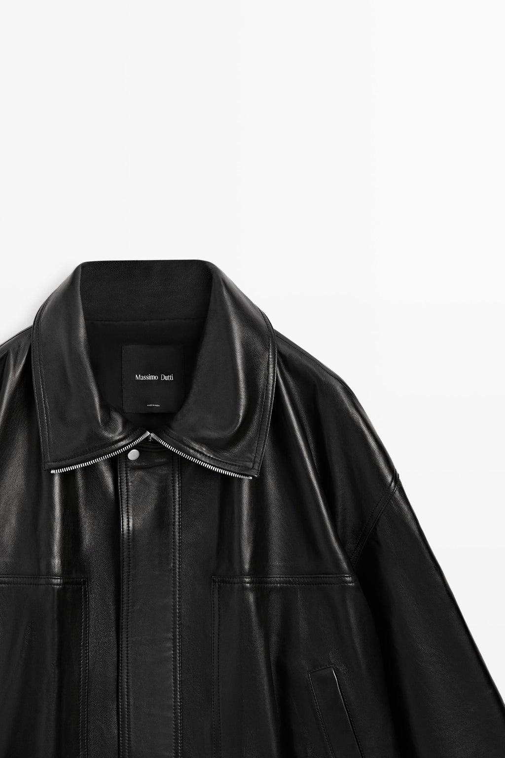 Close-up of a black leather jacket with a wide collar and front snap closure, photographed against a plain white background. 