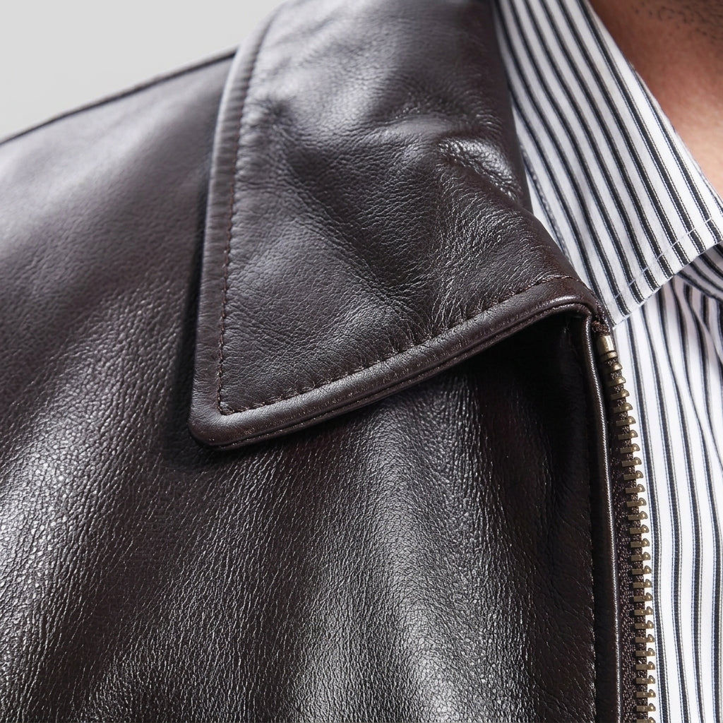 Close-up of a dark brown leather jacket with a pointed collar, worn over a black and white striped button-down shirt.