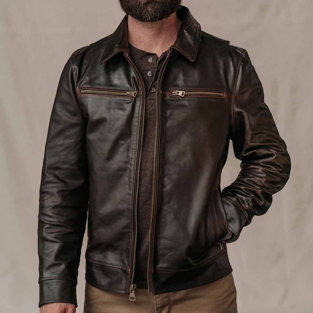 Brown leather jacket worn by a person on a beige background