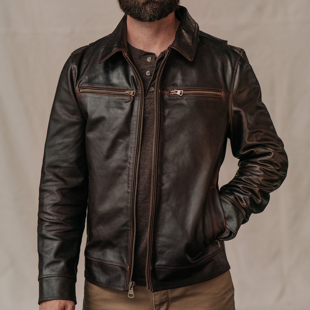 Brown leather jacket worn by a person on a beige background