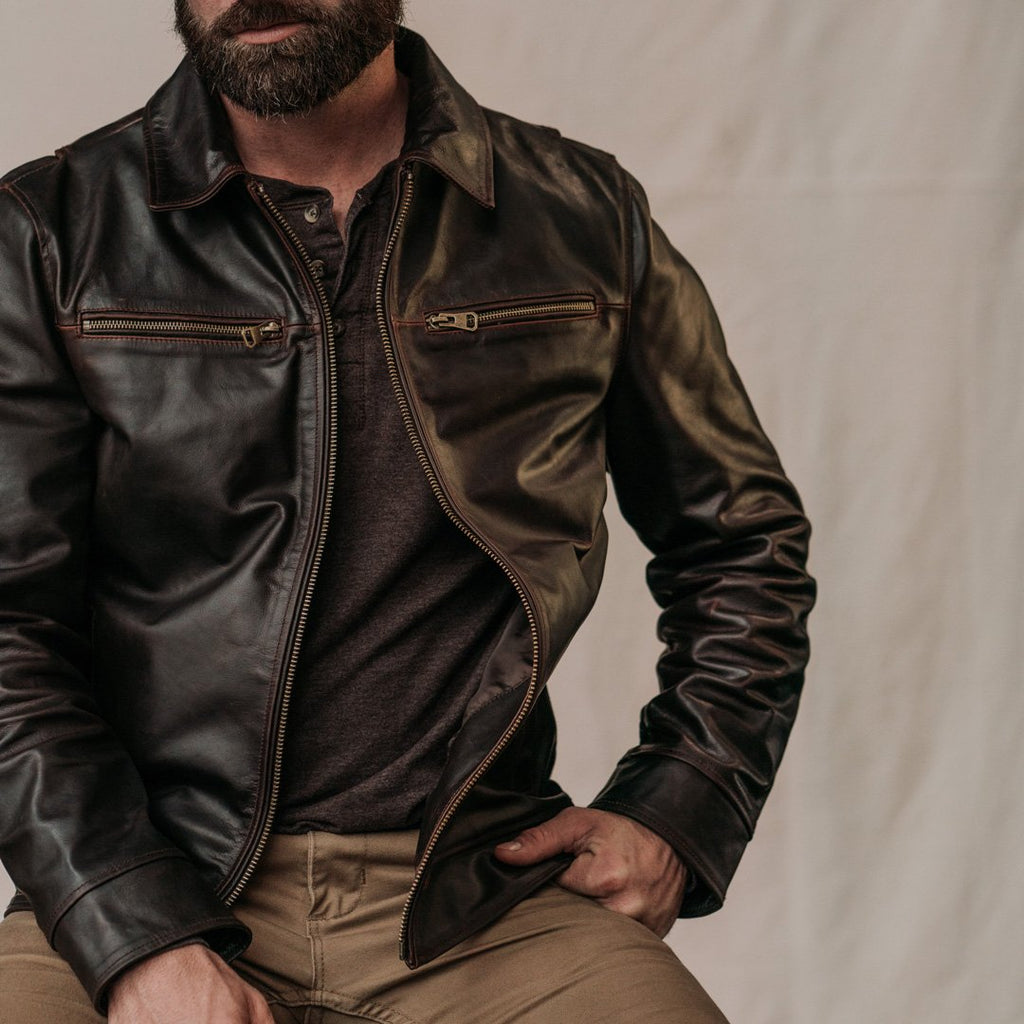 Man wearing a dark brown leather jacket on a plain background