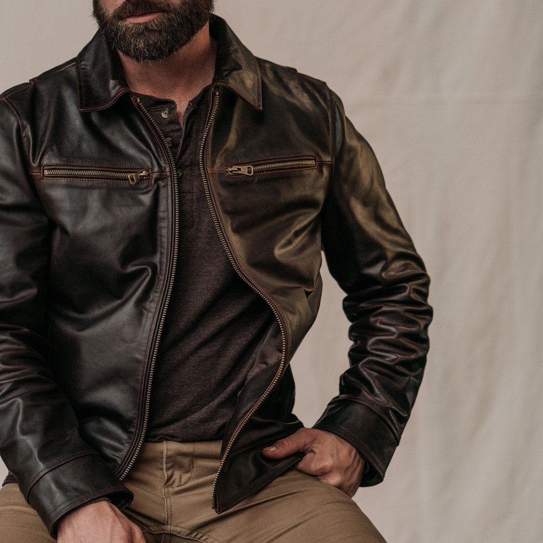 Man wearing a dark brown leather jacket on a plain background