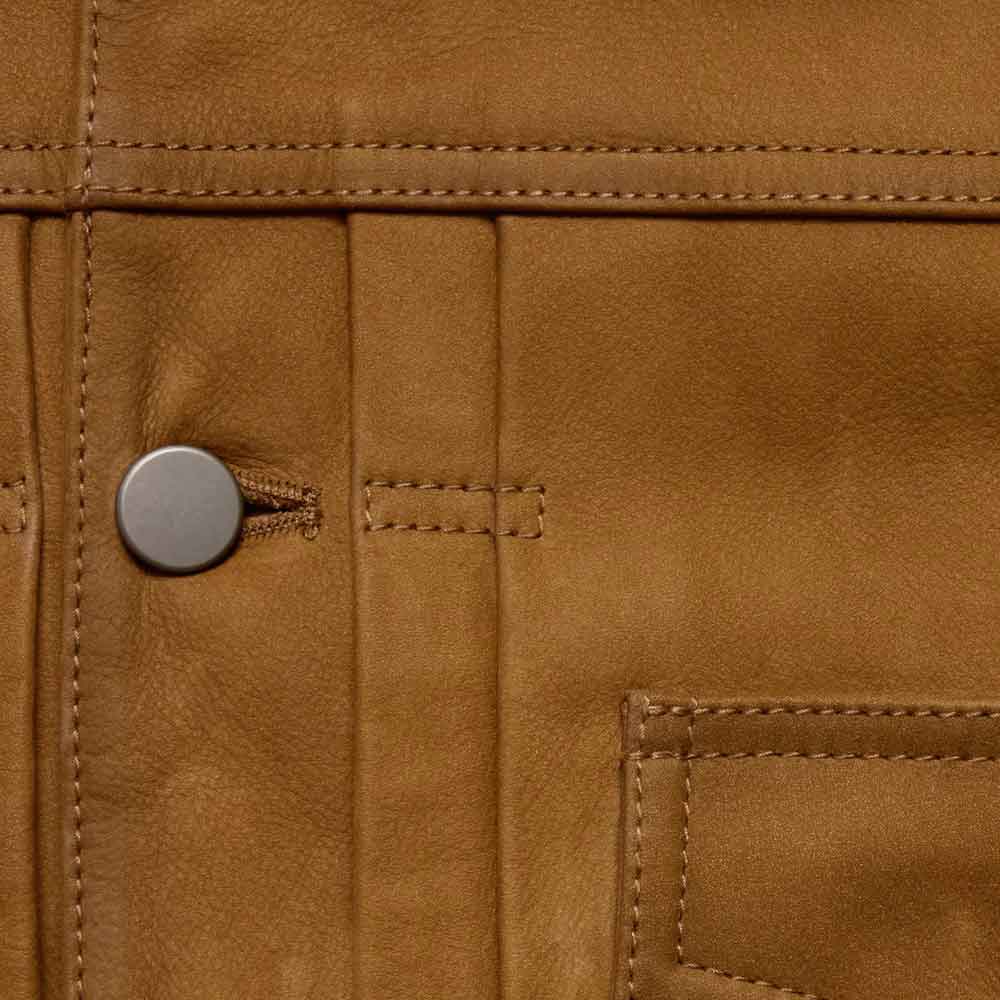 Close-up of a tan leather jacket showing the texture of the leather, a silver metal snap button, and detailed stitching.