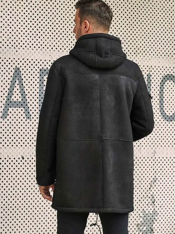 Person wearing a black leather jacket against a patterned wall.
