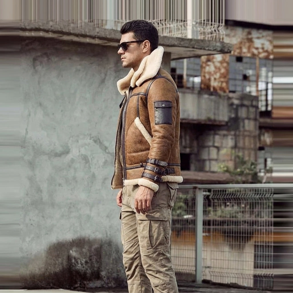 A man wearing a brown shearling-lined aviator jacket with a large cream collar, paired with beige cargo pants and sunglasses, standing in an urban outdoor setting.