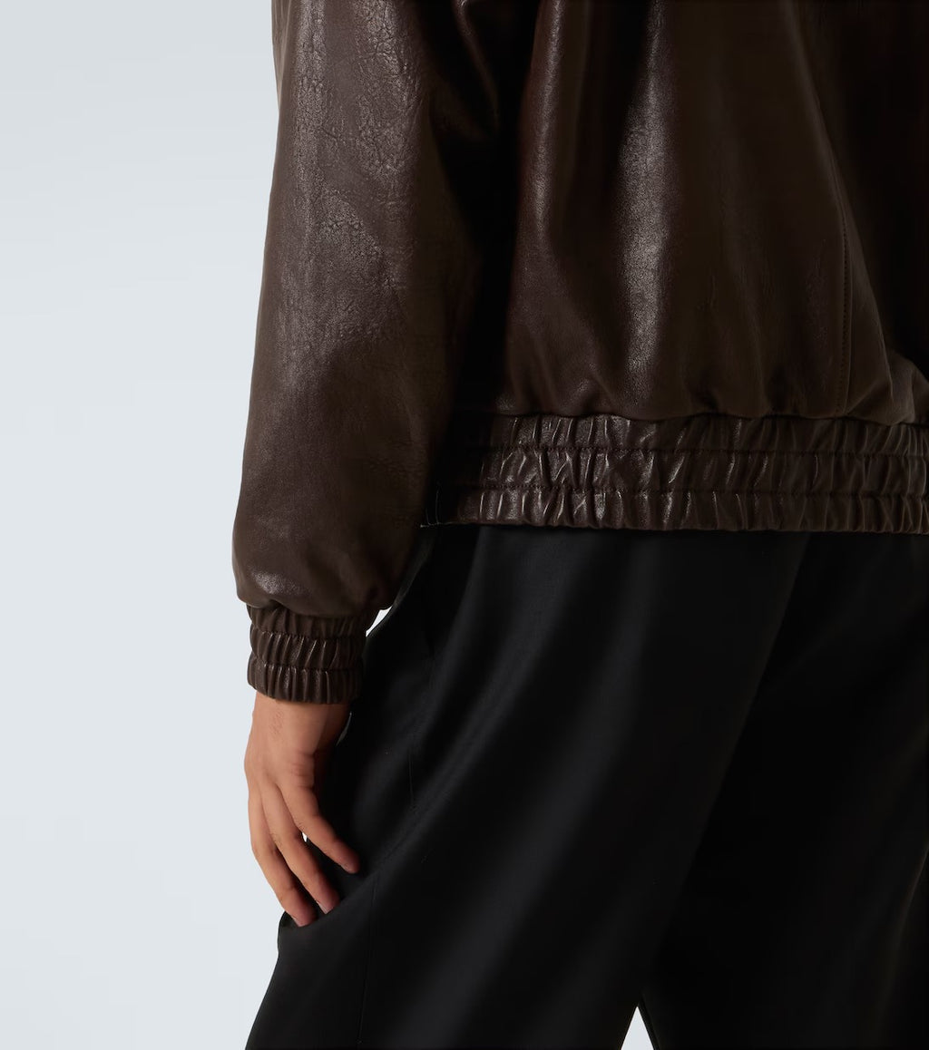 Brown leather jacket and black pants on a plain background