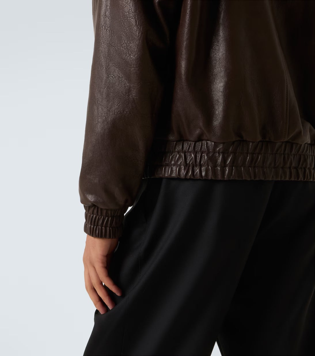 Brown leather jacket and black pants on a plain background