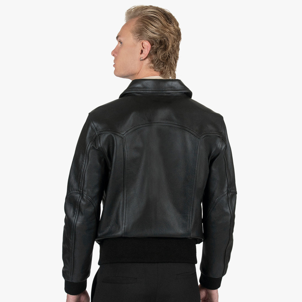 A man shown from the back wearing a black leather jacket with a high collar and ribbed cuffs, against a plain white background.