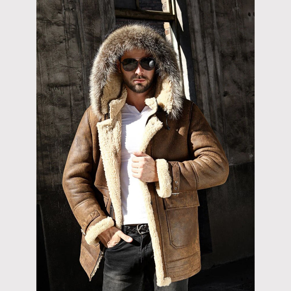 Man wearing a brown shearling coat with fur hood against a wooden background