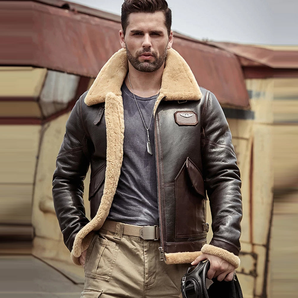 Man wearing a brown leather jacket with shearling collar in front of a vintage airplane.