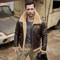 A man wearing a brown leather aviator-style jacket with a beige shearling lining, standing outdoors in front of a rusted vintage truck.