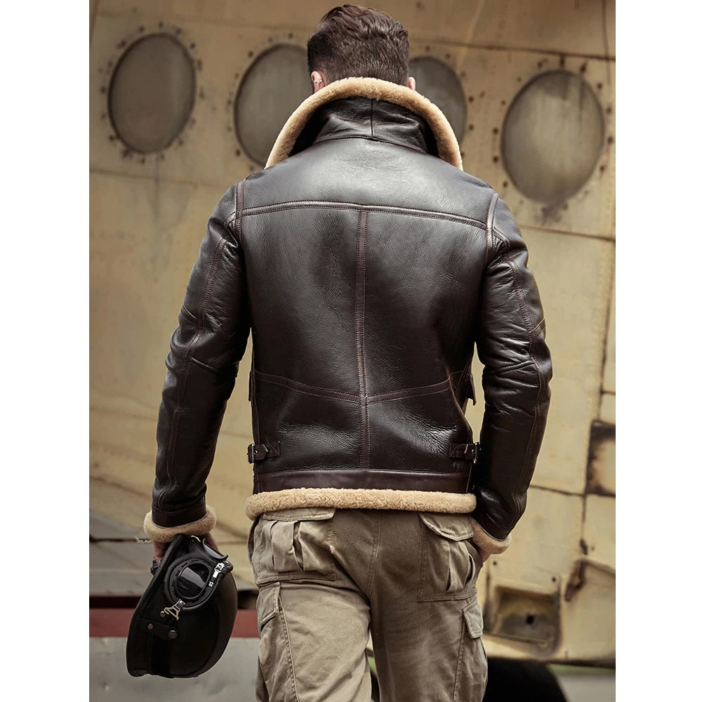 Person wearing a brown leather jacket with a helmet, standing in front of a vintage airplane.