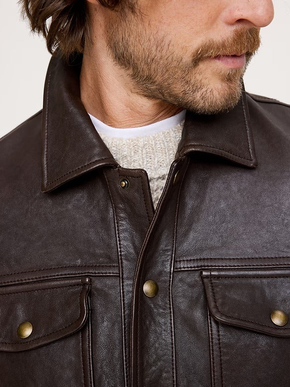 Close-up of a man wearing a dark brown leather jacket over a light beige knit sweater, showing the collar, front button closure, and chest pockets.