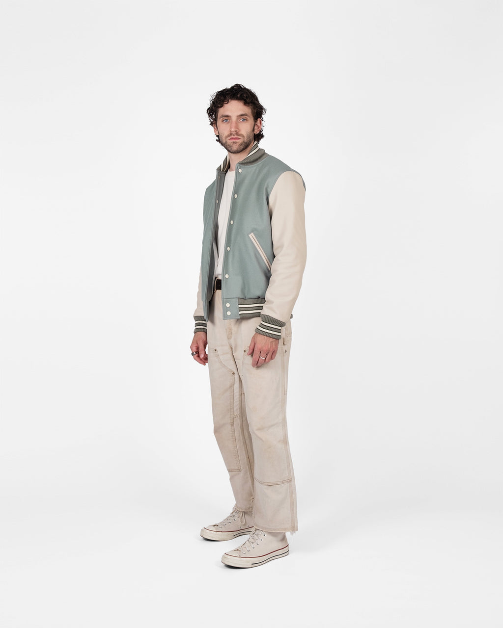 Man wearing a light green varsity jacket with dark green accents on a white background