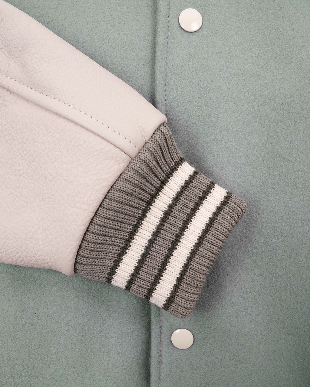 Close-up of a jacket sleeve with striped cuffs on a light green background