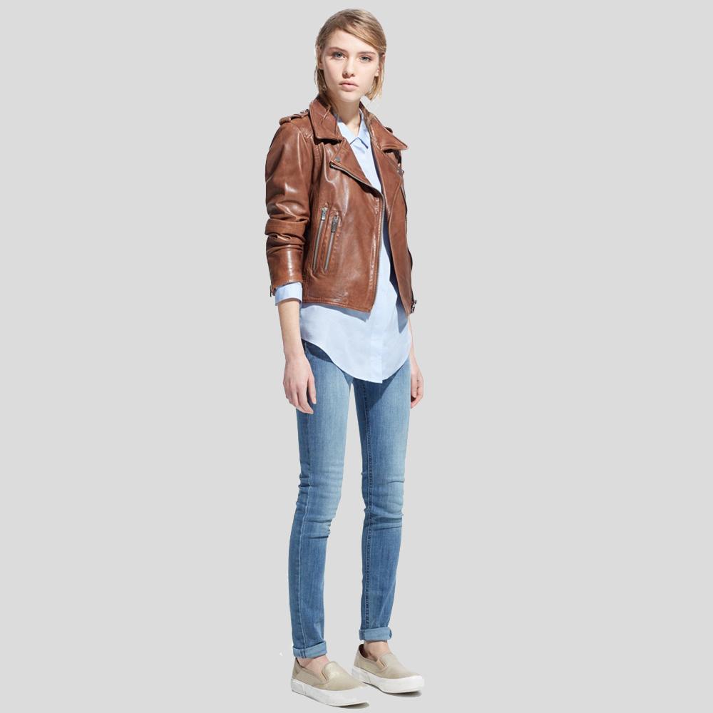 Woman wearing a brown leather jacket, light blue shirt, and jeans on a plain background