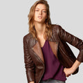 Woman wearing a brown leather jacket over a purple top on a light gray background